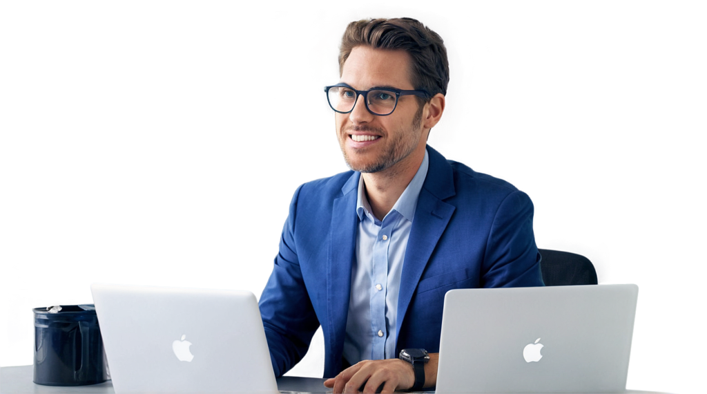 Man in a blue suit working on two laptops.
